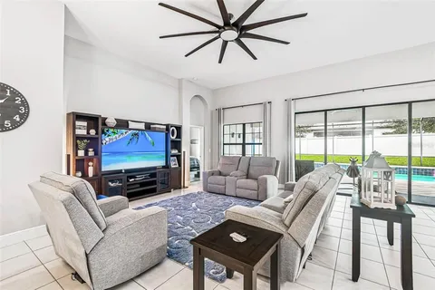 a living room with furniture a flat screen tv and a floor to ceiling window