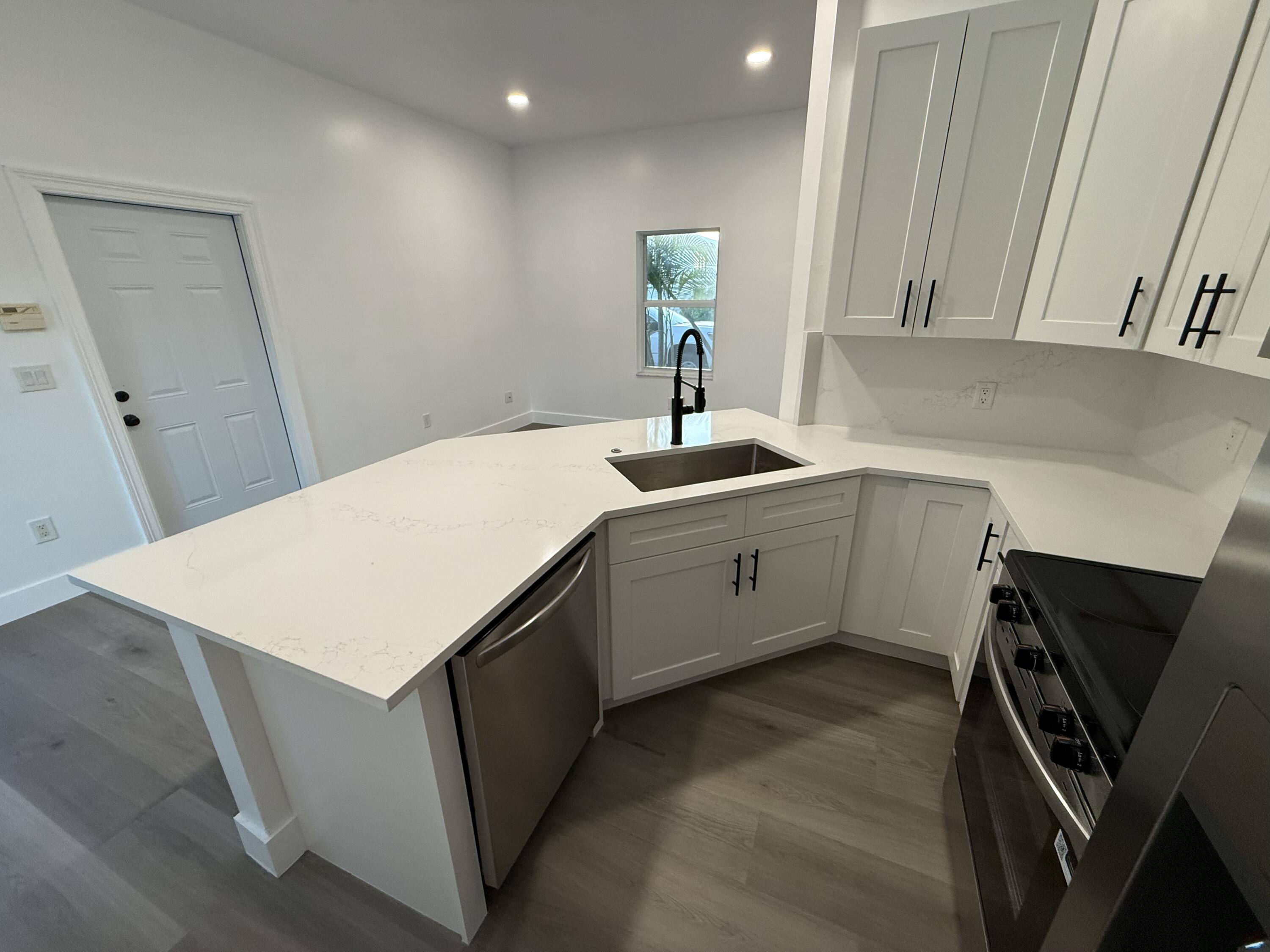 11865 Ellison Wilson Road, Unit A North Palm Beach, FL 33408 - Photo 4 of 12 a kitchen with a sink a stove and a refrigerator