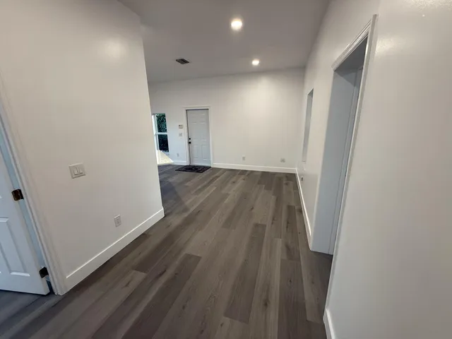an empty room with a chandelier fan and windows