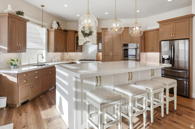 534 East Fish Hatchery Road Mantua, UT 84324 - Photo 23 of 87 Dual tone kitchen featuring stainless steel appliances, a kitchen breakfast bar, a center island, two tone color scheme, and backsplash