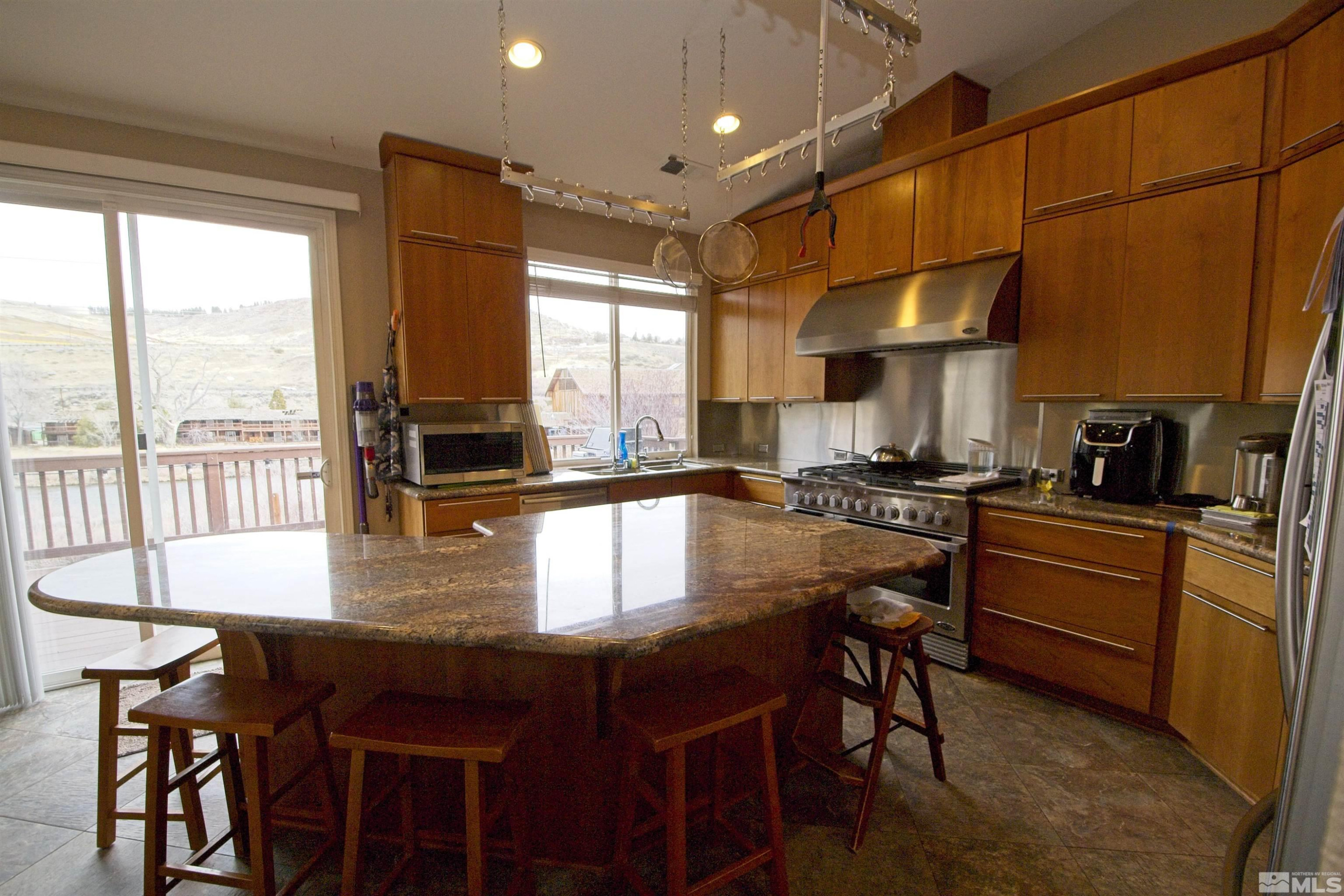 74 River Front Drive Reno, NV 89523 - Photo 7 of 28 a kitchen with stainless steel appliances granite countertop a stove a refrigerator a kitchen island a table and chairs with wooden floor
