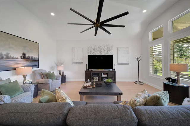 a living room with furniture a ceiling fan and a flat screen tv