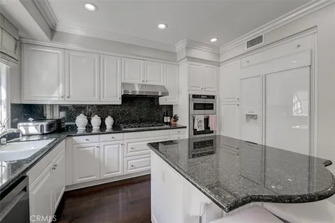 a kitchen with stainless steel appliances granite countertop a sink a stove and a refrigerator