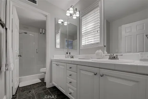 a bathroom with a double vanity sink toilet and a mirror