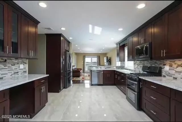 a large kitchen with stainless steel appliances wooden cabinets a stove and a sink