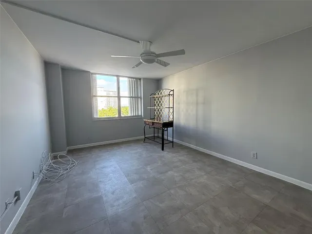 an empty room with windows and ceiling fan