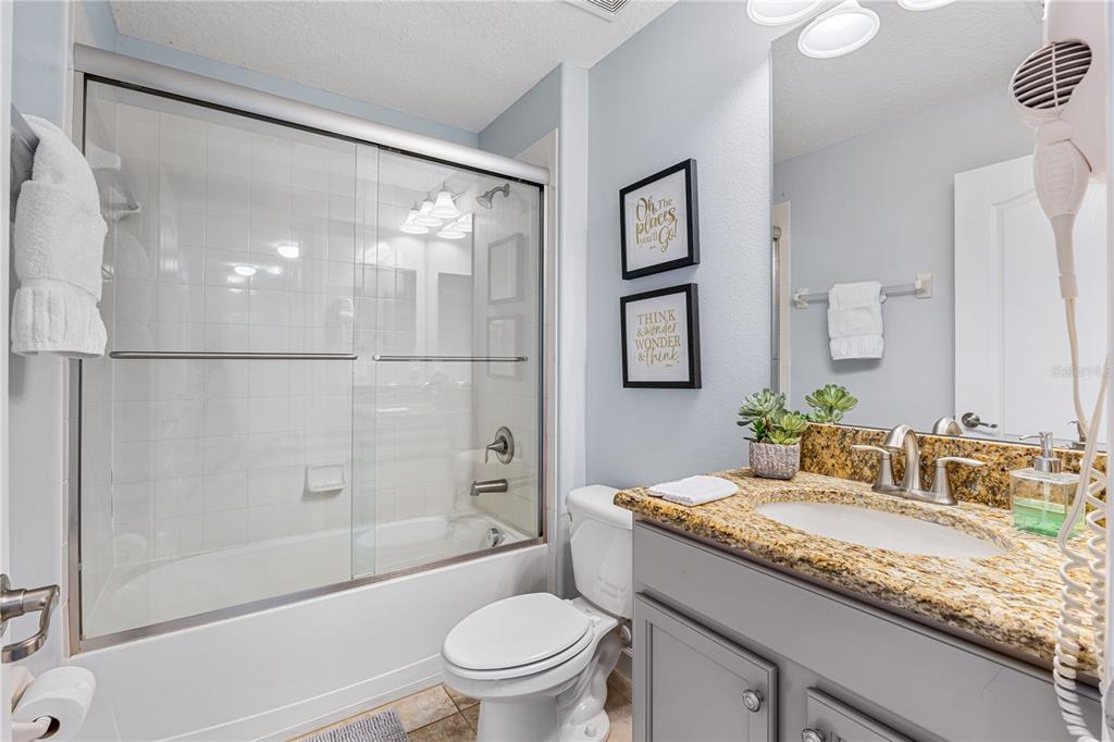 9006 Majesty Palm Road Kissimmee, FL 34747 - Photo 52 of 56 a bathroom with a granite countertop sink a toilet and shower