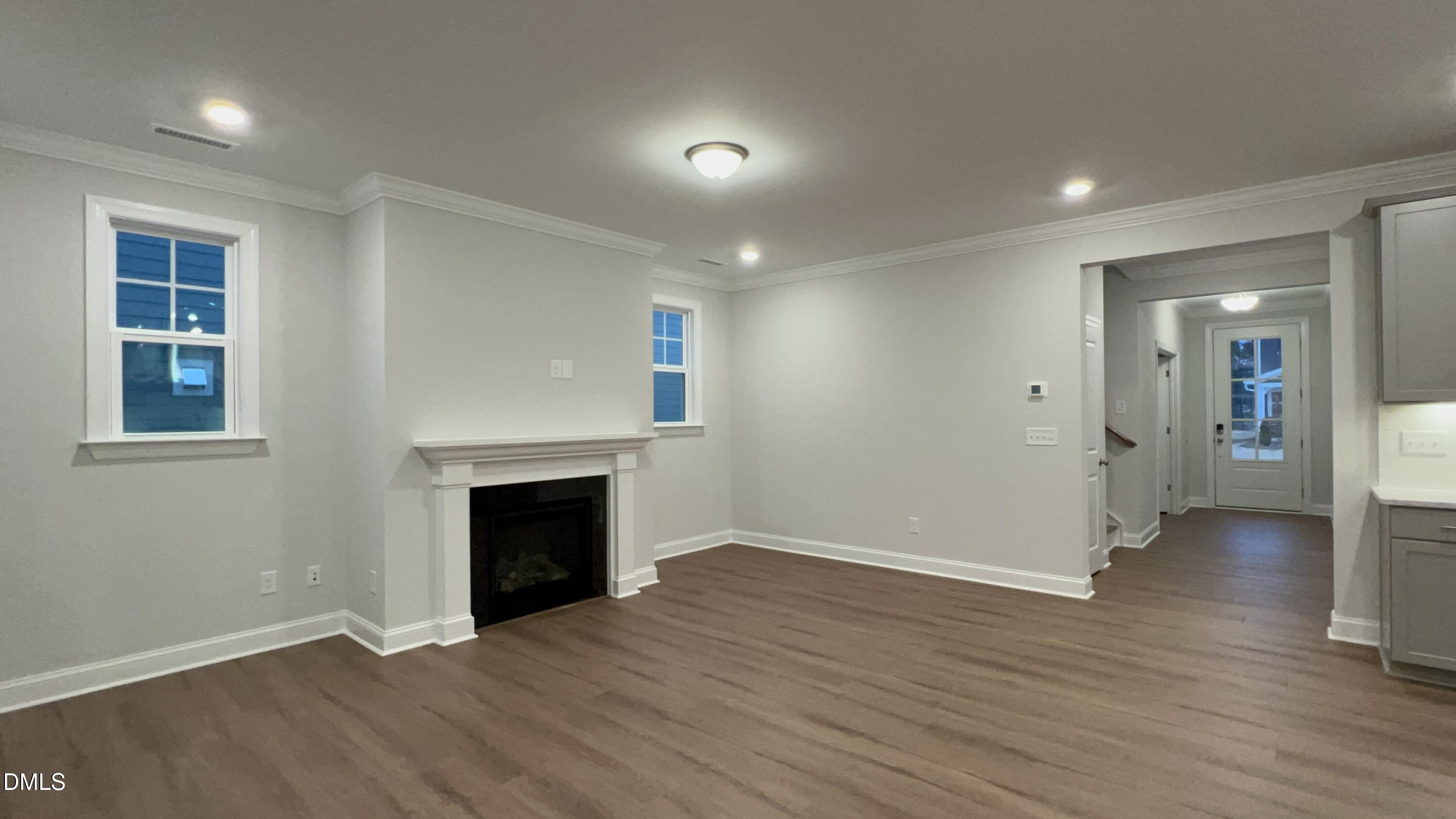 113 Corapeake Way Holly Springs, NC 27539 - Photo 5 of 20 an empty room with wooden floor fireplace and windows