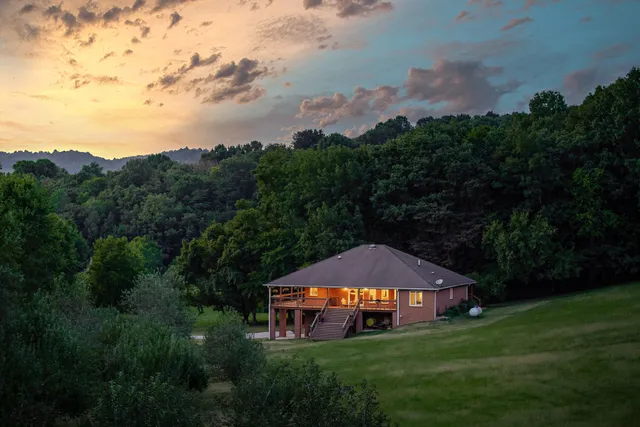 a view of a big house with a big yard and large trees