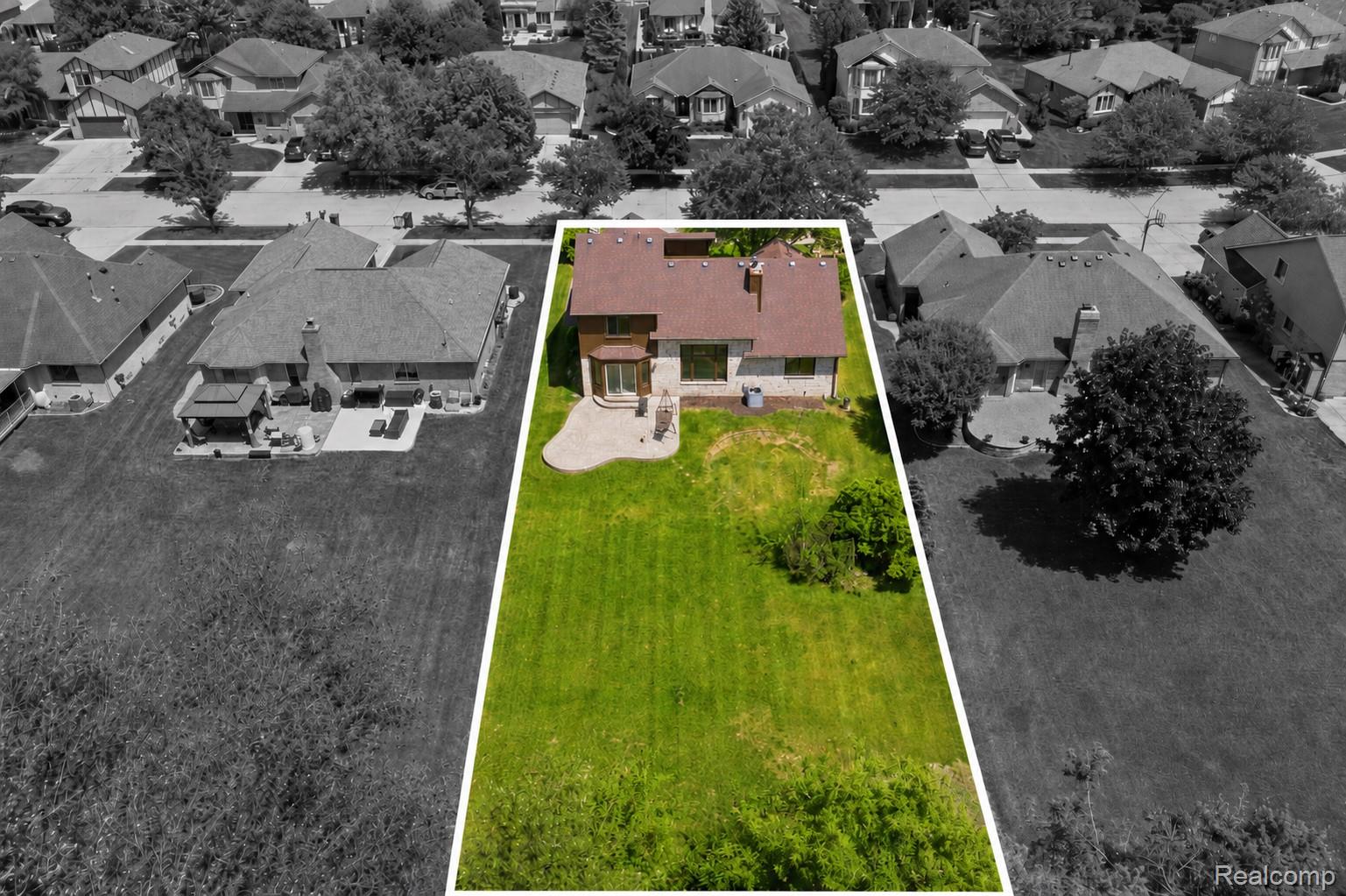 52658 Stag Ridge Drive Macomb, MI 48042 - Photo 3 of 28 Expansive green lawn with mature trees and a stone patio featuring a curved design