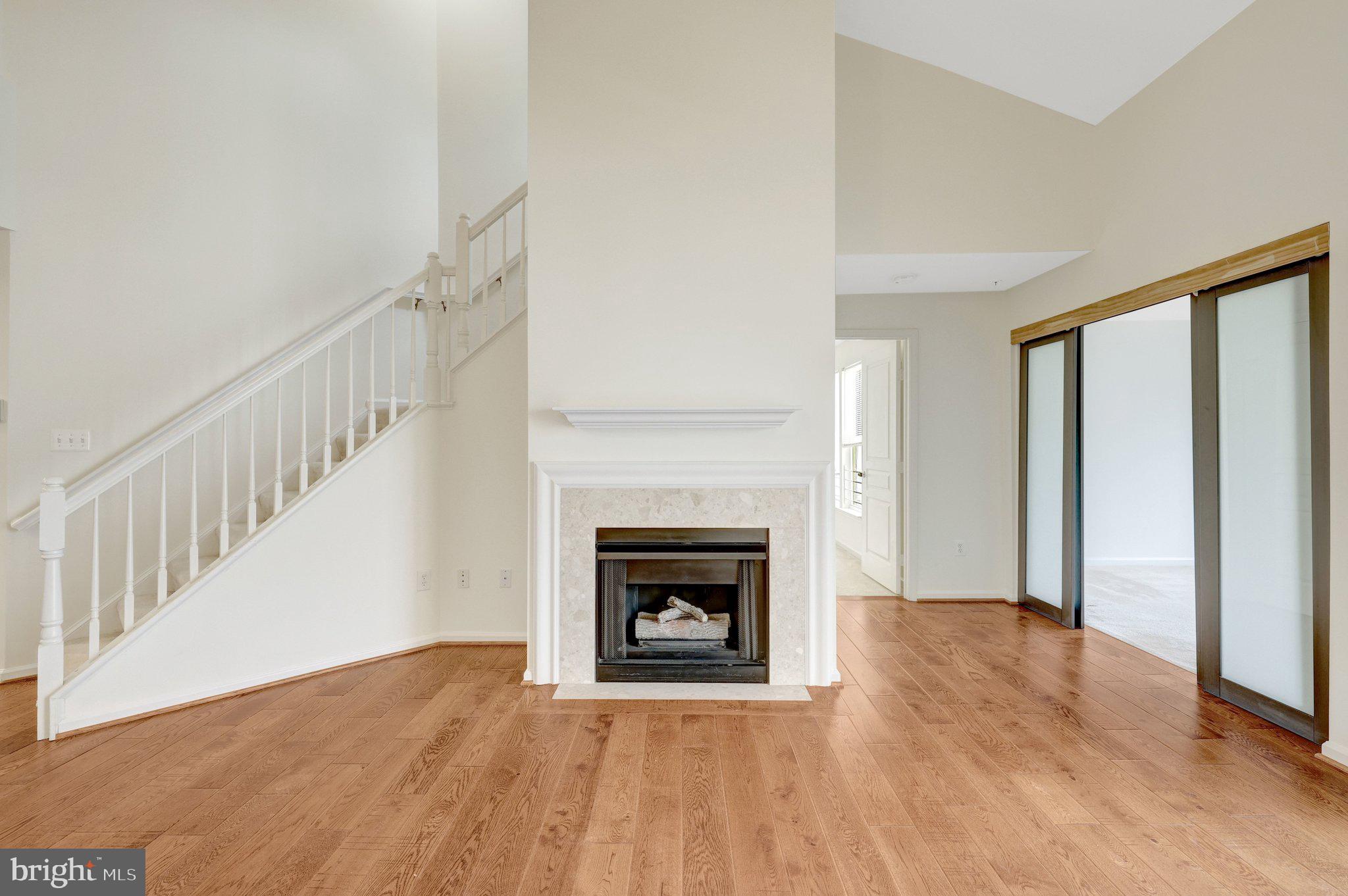 12001 Market Street, Unit 434 Reston, VA 20190 - Photo 15 of 43 a view of an empty room with wooden floor fireplace and a window