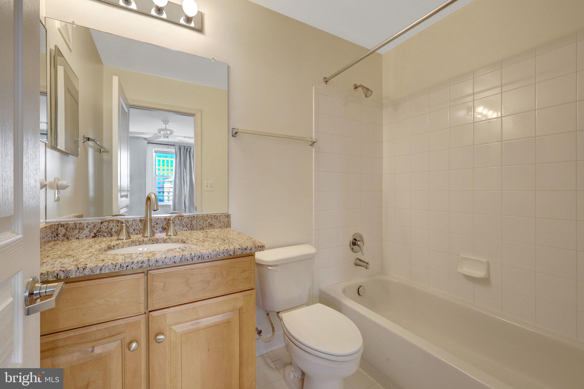 12001 Market Street, Unit 434 Reston, VA 20190 - Photo 29 of 43 a bathroom with a granite countertop sink toilet and shower