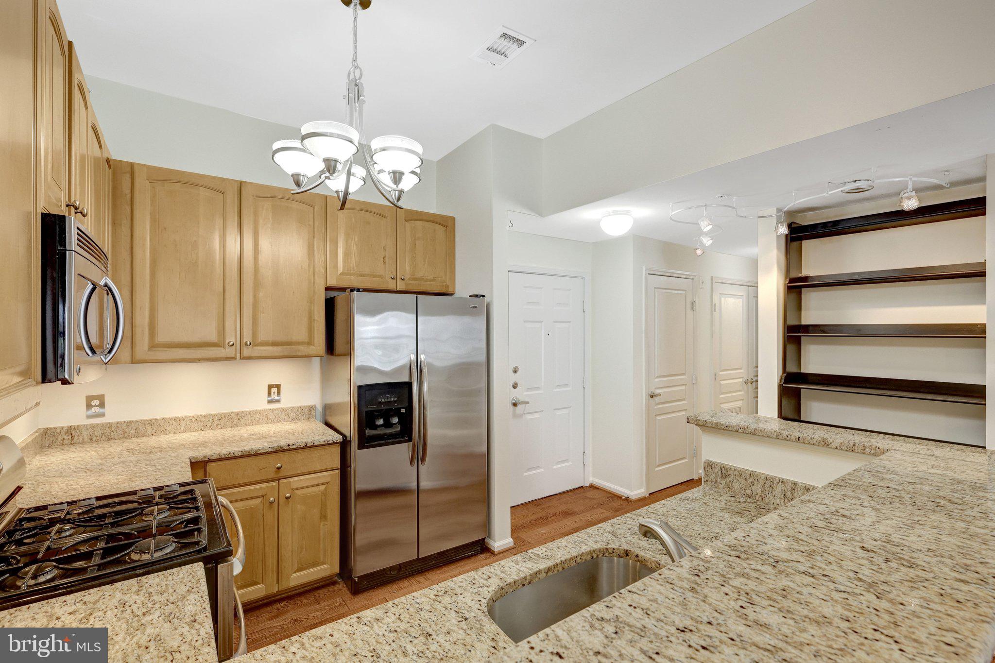 12001 Market Street, Unit 434 Reston, VA 20190 - Photo 8 of 43 a kitchen with a refrigerator a stove and cabinets