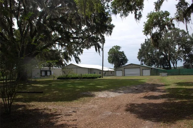 a view of a big house with a big yard and large trees