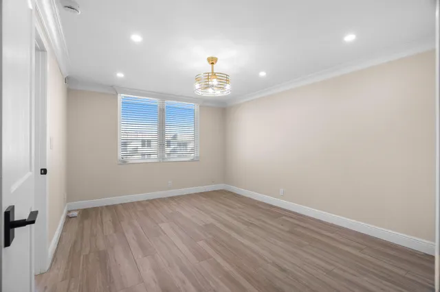 an empty room with wooden floor cabinet and windows