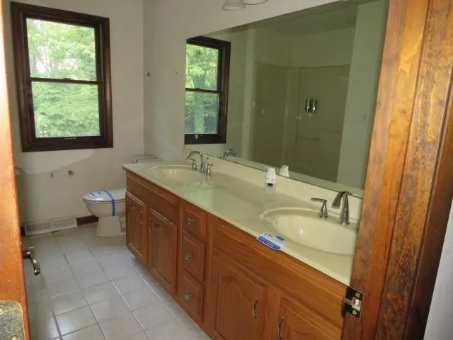 a spacious bathroom with a granite countertop sink a toilet and a mirror