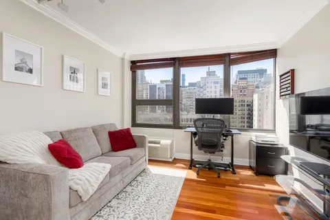 a living room with furniture a flat screen tv and a floor to ceiling window