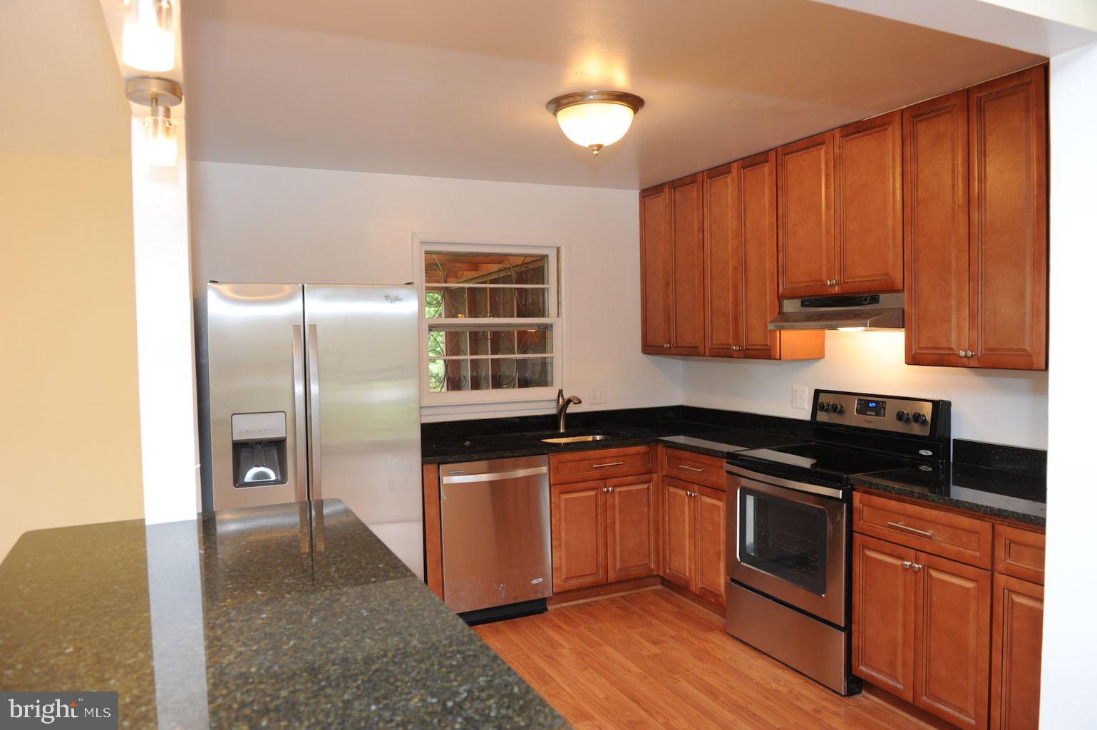 1342 Mayflower Drive McLean, VA 22101 - Photo 5 of 14 a kitchen with stainless steel appliances granite countertop a refrigerator a sink dishwasher and wooden cabinets with wooden floor