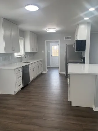 a large kitchen with wooden floors and stainless steel appliances