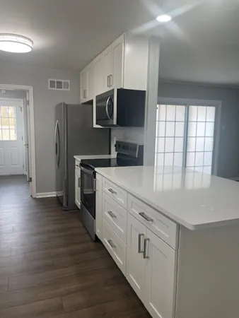 a kitchen with stainless steel appliances white cabinets and wooden floor