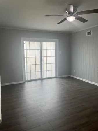 a view of an empty room with a window and wooden floor