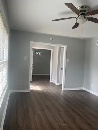a view of an empty room with wooden floor and a window