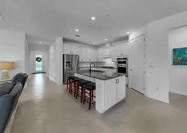a kitchen with stainless steel appliances kitchen island granite countertop a refrigerator and a sink