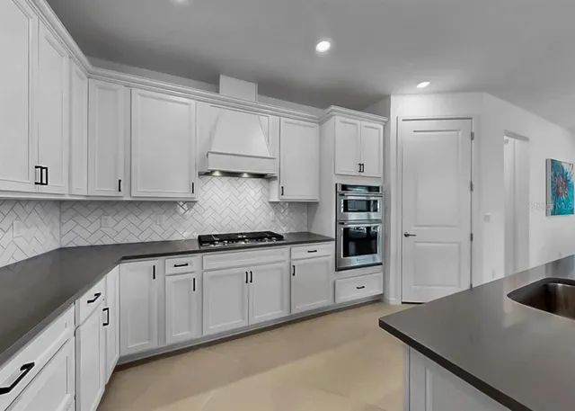 a kitchen with stainless steel appliances granite countertop a refrigerator and a stove top oven