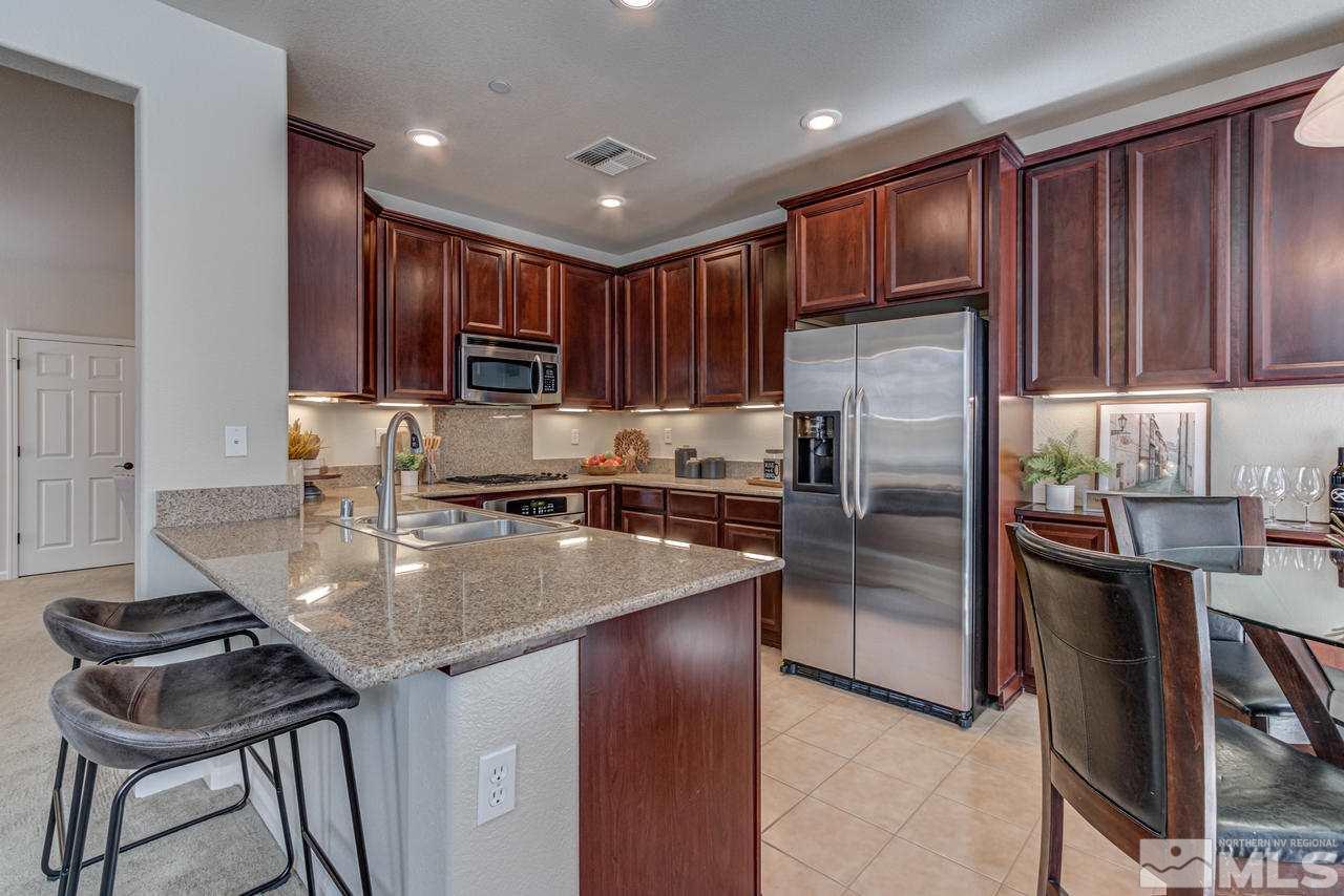 1808 Wind Ranch Road, Unit B Reno, NV 89521 - Photo 10 of 31 a kitchen with kitchen island granite countertop wooden cabinets a refrigerator and a stove