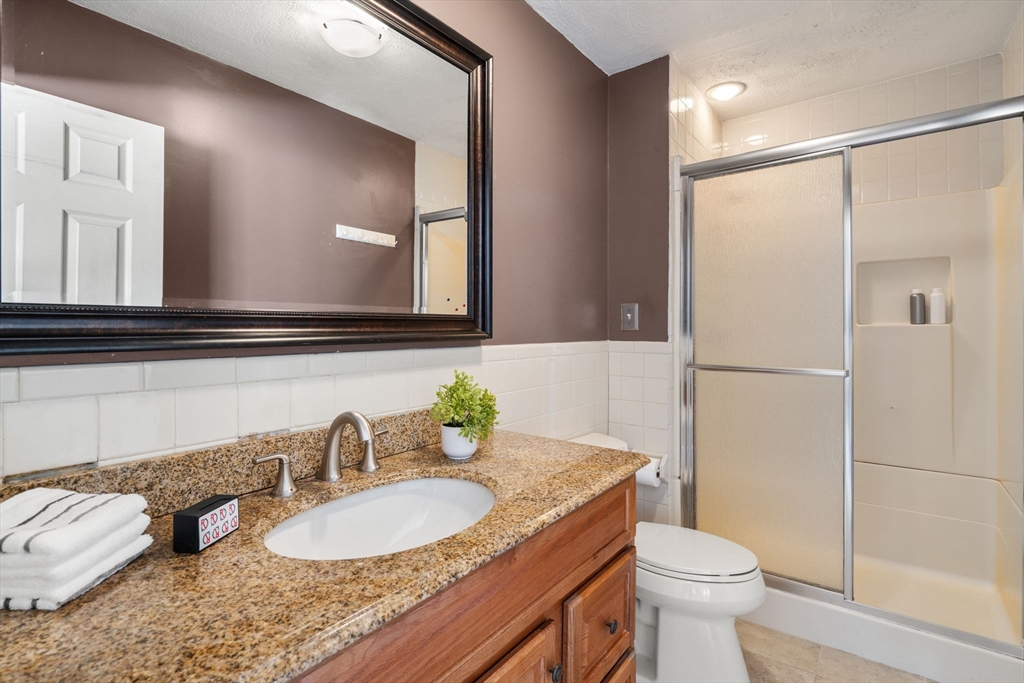 9 April Lane, Unit 9 Lexington, MA 02421 - Photo 25 of 38 a bathroom with a granite countertop sink mirror vanity and toilet