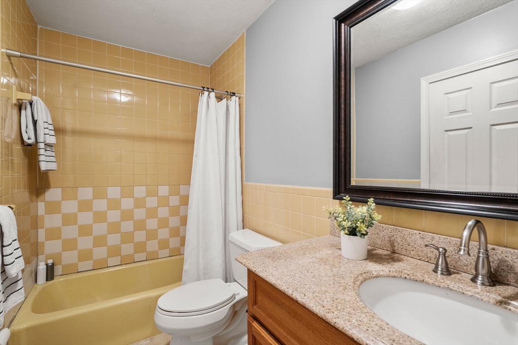 9 April Lane, Unit 9 Lexington, MA 02421 - Photo 32 of 38 a bathroom with a granite countertop sink toilet mirror and shower