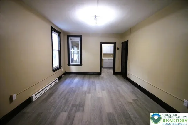 an empty room with wooden floor and windows