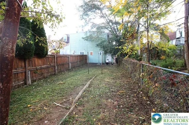 a view of a yard with wooden fence