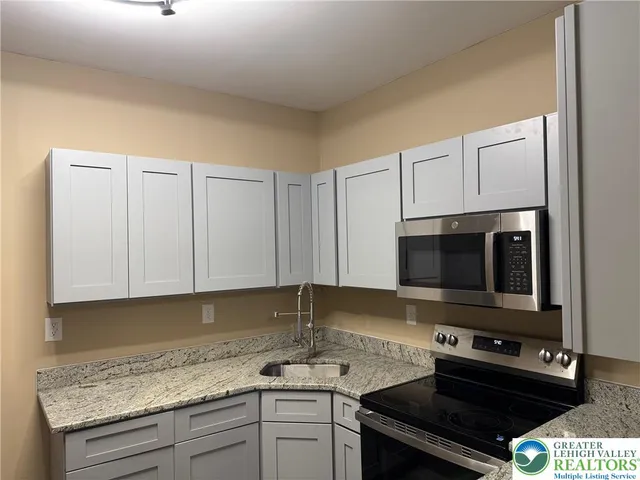 a kitchen with granite countertop a sink and a stove top oven
