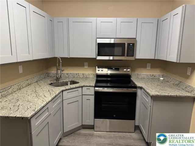 a kitchen with granite countertop a sink stove and microwave