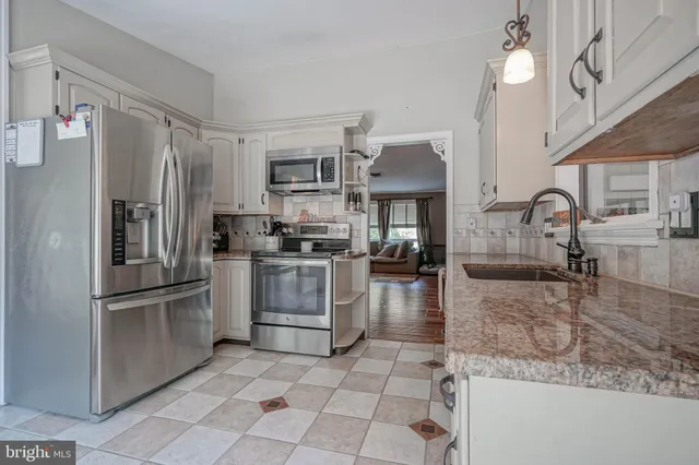 a kitchen with stainless steel appliances granite countertop a refrigerator a stove and a sink