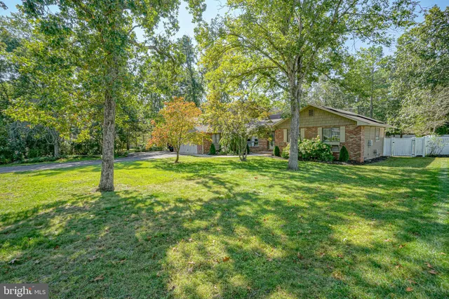 a view of a house with a big yard and large trees