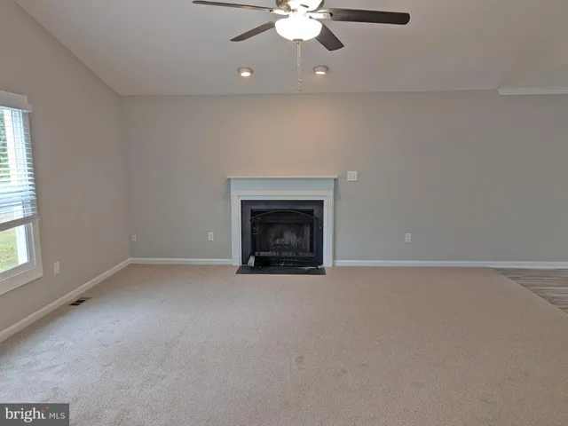 an empty room with chandelier fan and windows
