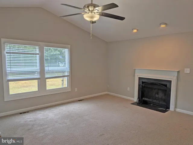 an empty room with chandelier fan and windows