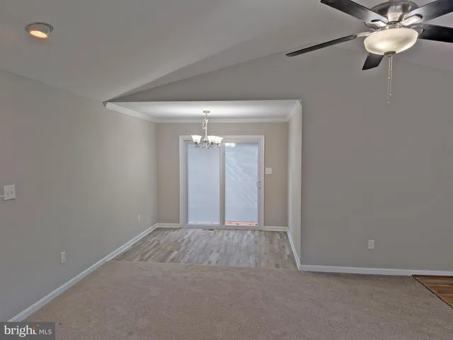a view of an empty room with a chandelier fan