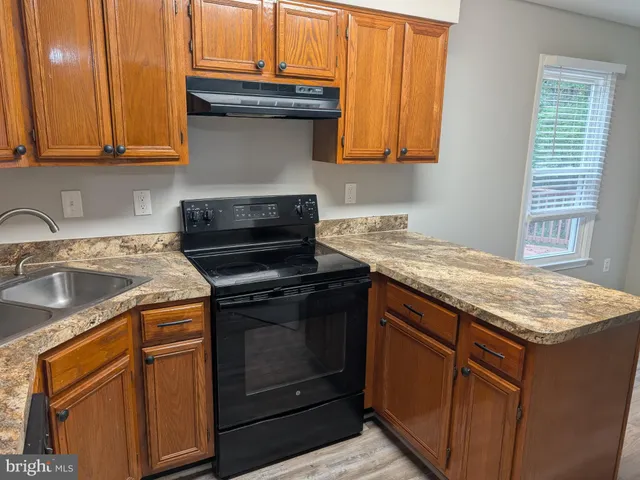 a kitchen with granite countertop a sink stove and cabinets
