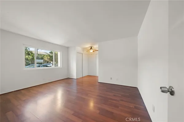 an empty room with wooden floor and windows