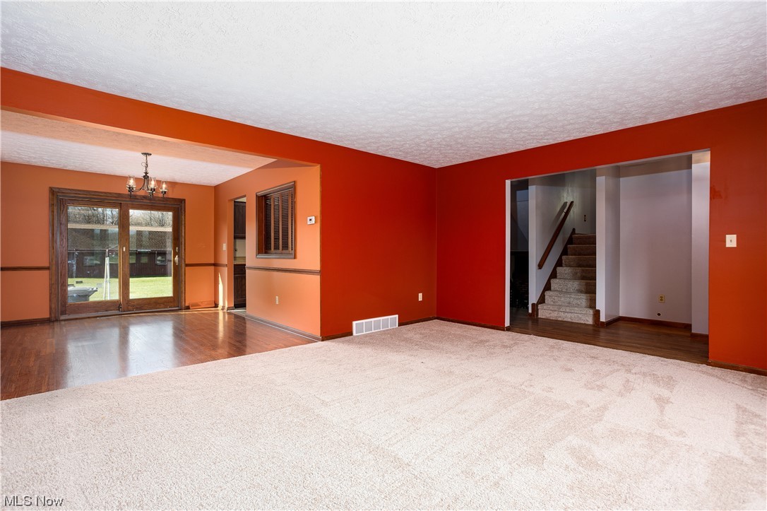 5680 Lance Road Medina, OH 44256 - Photo 12 of 32 Empty room with dark carpet, a notable chandelier, and a textured ceiling