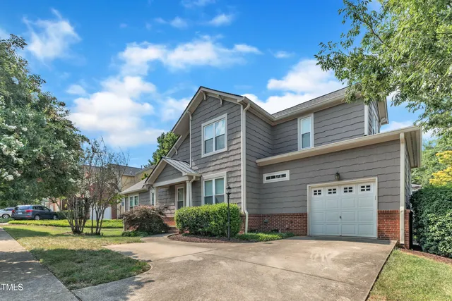 a front view of a building with a garden and trees