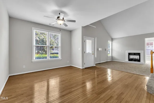 a view of an empty room with wooden floor and a window