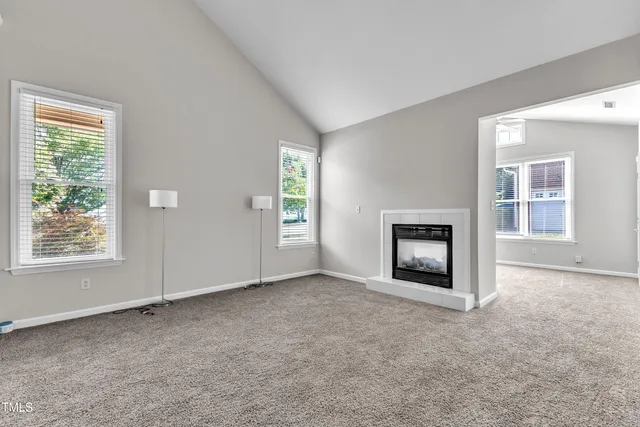 an empty room with windows and fireplace