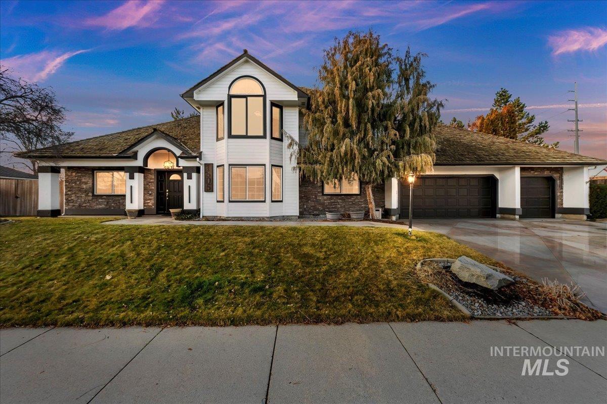 View of front of house with a garage, concrete driveway, and a lawn