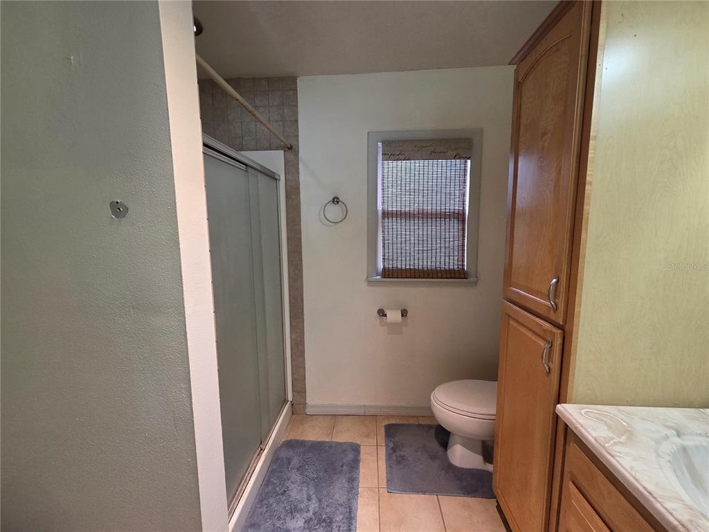 124 East F Street Frostproof, FL 33843 - Photo 27 of 37 a bathroom with a granite countertop toilet a sink a shower and a window