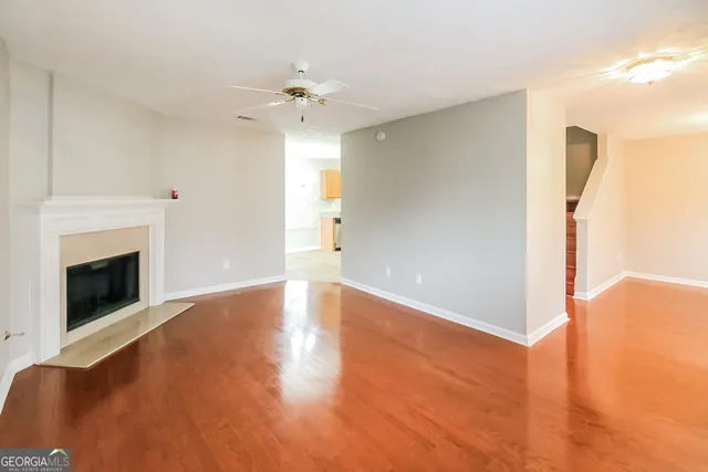 a view of an empty room with chandelier fan and fire place