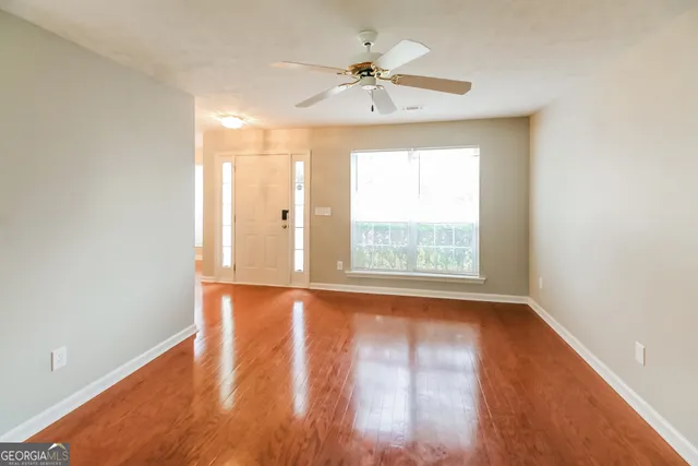 a view of an empty room with wooden floor and a window